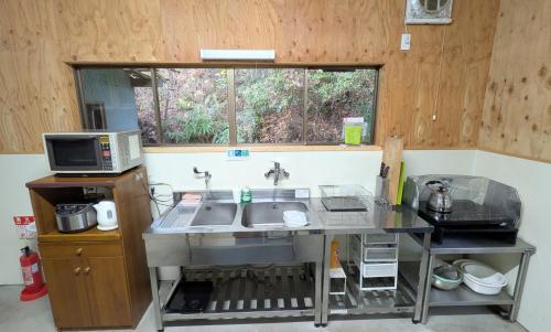 a kitchen with a sink and a microwave at 宿屋まてまて Villa Mate Mate in Sawara