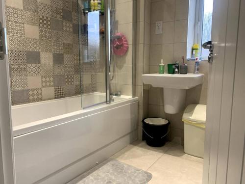 a bathroom with a tub and a toilet and a sink at Spacious Room With Kingsize Bed in Dinnington