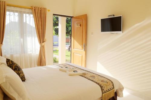 a bedroom with a bed with a television on the wall at Whiterose Guesthouse in Senggigi