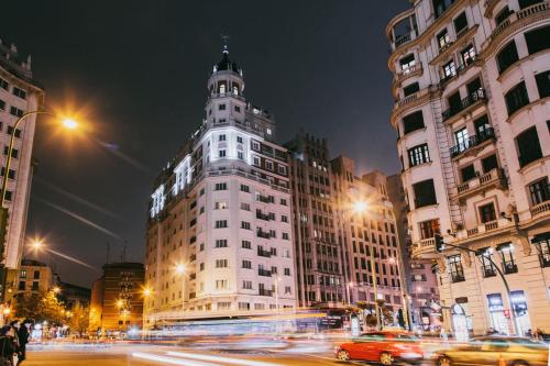 duży budynek z wieżą na ulicy miejskiej w nocy w obiekcie Dear Hotel Madrid w Madrycie