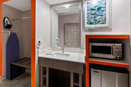a small bathroom with a sink and a microwave at Howard Johnson by Wyndham Jackson in Jackson