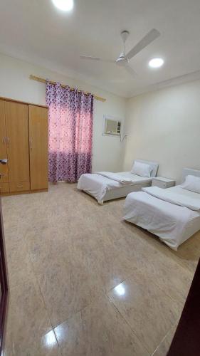 a bedroom with two beds and a pink curtain at Salalah Peace House in Salalah