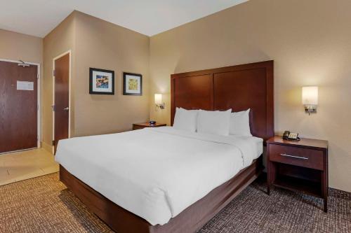 a hotel room with a large bed with white sheets at Comfort Inn Lathrop Stockton Airport in Lathrop