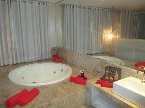 ein Badezimmer mit großer Badewanne und Waschbecken in der Unterkunft Victor Plaza Formiga in Formiga