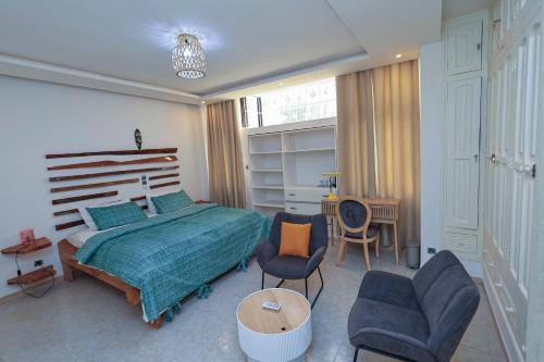 Un dormitorio con una cama y dos sillas y una mesa. en Villa Rosa Cotonou, en Cotonou