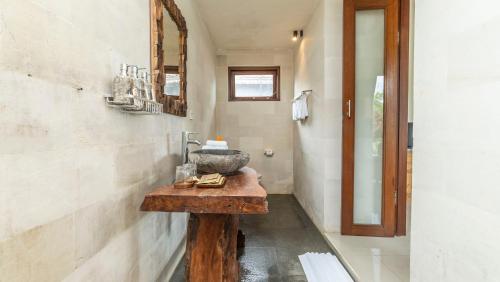 a bathroom with a stone sink on a wooden table at Tenggala Villa Ubud by Mahaputra in Ubud
