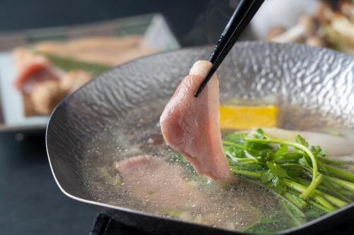 a piece of meat is cooking in a wok at Mizunoto Reopening on April 1, 2025 in Hakone