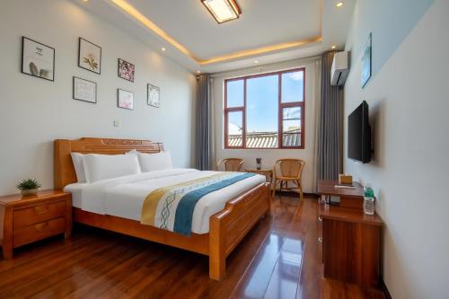 a hotel room with a bed and a television at Dali Ancient Town-Jinbi Yayuan Inn in Dali