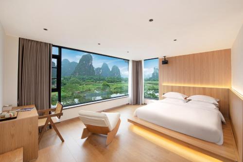 a bedroom with a large bed and a desk and a chair at Yangshuo Hidden Dragon Villa in Yangshuo