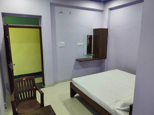 a bedroom with a bed and a chair and a green door at Hotel Shree Ram in Kishangarh