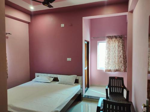 a bedroom with pink walls and a bed and a chair at Hotel Shree Ram in Kishangarh