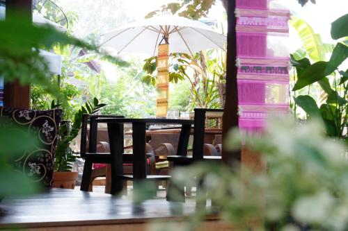 uma mesa e cadeiras com um guarda-sol num alpendre em Kittawan Home&Gallery em Chiang Mai