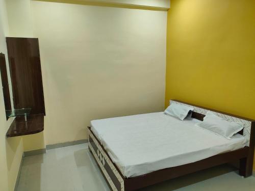 a small bed in a room with a yellow wall at Hotel Shree Ram in Kishangarh