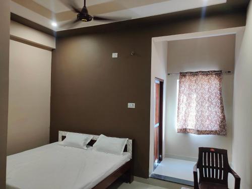 a bedroom with a bed and a window and a chair at Hotel Shree Ram in Kishangarh