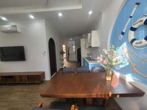 a dining room with a wooden table and a kitchen at Villa 4 bedrooms, 5 bathrooms, sea view at NovaWorld Phan Thiet 53 in Bình Tú