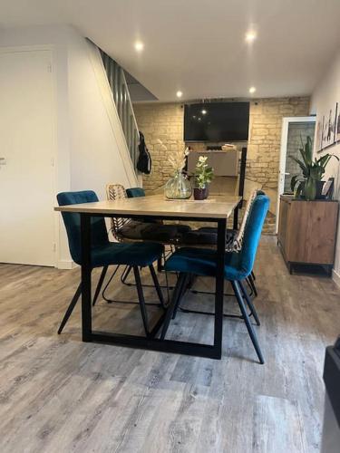 - une table à manger avec des chaises bleues dans l'établissement Maison à Luc sur Mer, à Luc-sur-Mer
