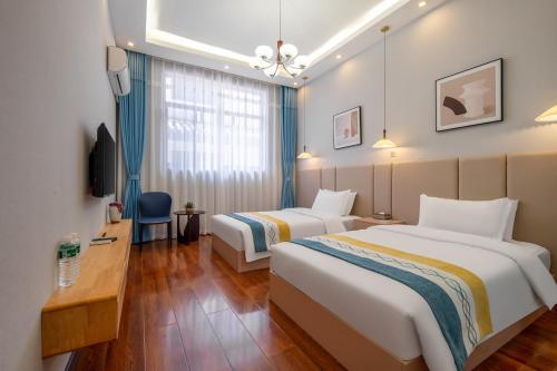 a hotel room with two beds and a desk at Dali Ancient Town-Jinbi Yayuan Inn in Dali