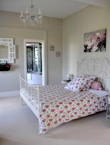 a bedroom with a white bed with a floral bedspread at Château De Matel in Roanne