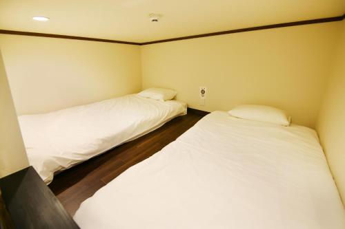 two beds in a small room with white sheets at Mt Fuji Glamping TOURIST VILLA Kawaguchiko in Fujikawaguchiko