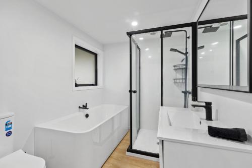 a white bathroom with a sink and a shower at Family Holiday at the Beach! in Pukehina