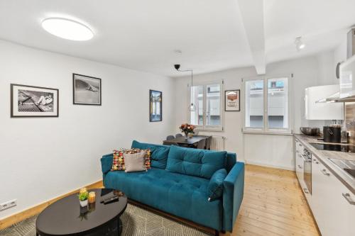a living room with a blue couch and a kitchen at Residenz im historischen Zentrum - Aalen Apartments & Suites in Aalen