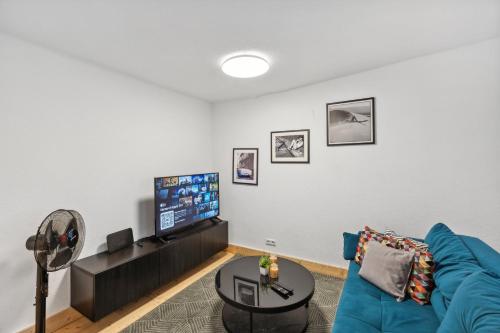 a living room with a blue couch and a flat screen tv at Residenz im historischen Zentrum - Aalen Apartments & Suites in Aalen
