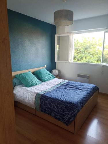 une chambre avec un lit aux murs bleus et une fenêtre dans l'établissement Appartement Centre Ville , Saint Sever, à Saint-Sever