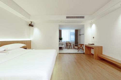 a white bedroom with a bed and a desk at Yangshuo Hidden Dragon Villa in Yangshuo