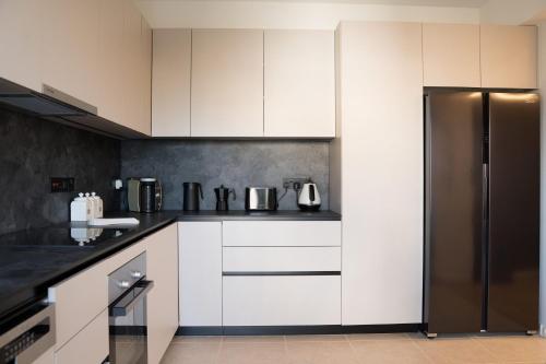 a kitchen with white cabinets and a refrigerator at Delightful 1st Floor Xanthippis Apartment in Strovolos