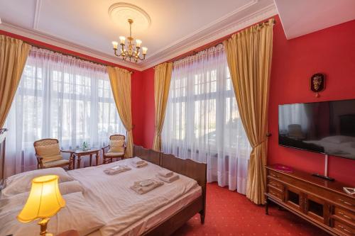 a bedroom with a bed and a flat screen tv at Willa Barbara - ProHarmonia in Lądek-Zdrój