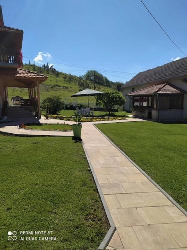 a walkway next to a house with a grass yard at Etno kutak Jaćimović in Gornji Milanovac