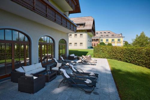 a patio with a group of chairs and a house at Arabella Jagdhof Resort am Fuschlsee, a Tribute Portfolio Hotel in Hof bei Salzburg