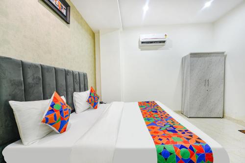 a bedroom with a large white bed with colorful pillows at FabHotel Kavya Inn - Nr The Mall of Faridabad in Faridabad