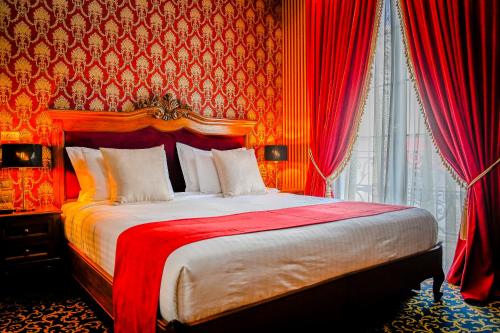 a bedroom with a large bed with red curtains at Envy Hotel in Durrës