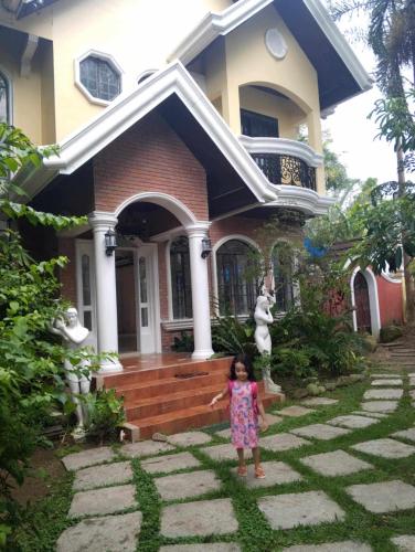 una bambina in piedi davanti a una casa di Princess Muffin Resort a Calamba