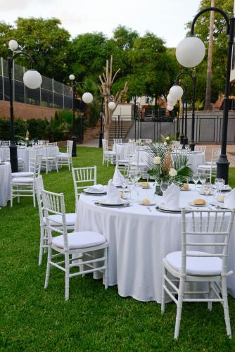 a table with white tables and chairs on the grass at Hotel San Pablo Sevilla in Seville