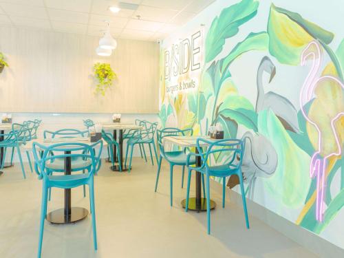 a room with tables and chairs and a mural at ibis Styles Goiania Marista in Goiânia