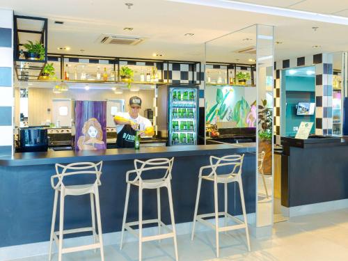 a bar in a restaurant with three bar stools at ibis Styles Goiania Marista in Goiânia