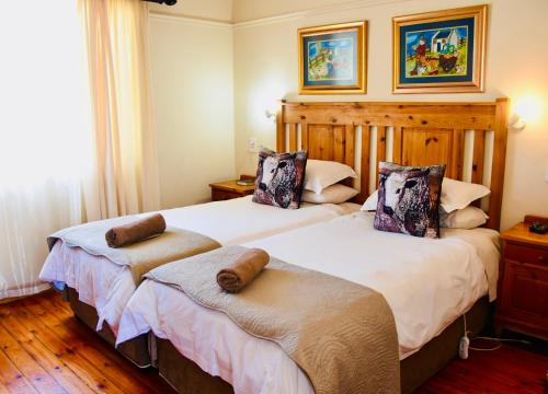 two beds in a room with wooden floors at Donkin Country House in Beaufort West