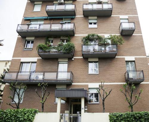 ボローニャにあるIn Fiera 14 Apartmentのバルコニーと植物が備わる高いレンガ造りの建物