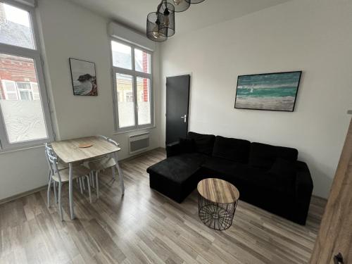 un salon avec un canapé noir et une table dans l'établissement Amiens, appart douillet 2-4P, à Amiens