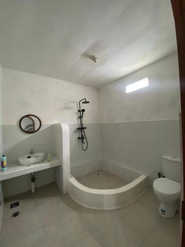 a white bathroom with a toilet and a sink at Alaya at volcano in Baturaja