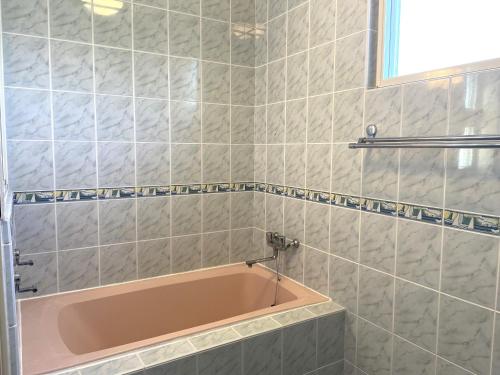 a bathroom with a pink bath tub in it at Ocean Terrace金武 in Kin