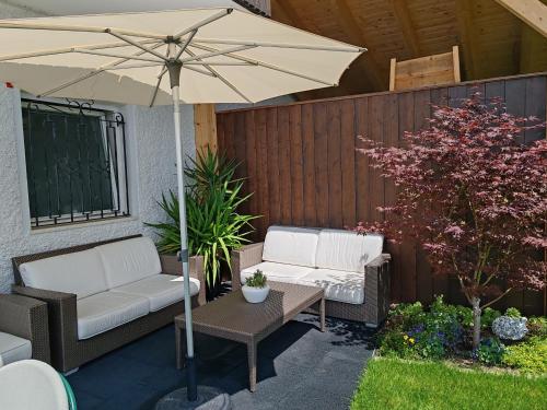 a patio with two chairs and an umbrella at Schenna Garni Eden Bed & Breakfast in Schenna