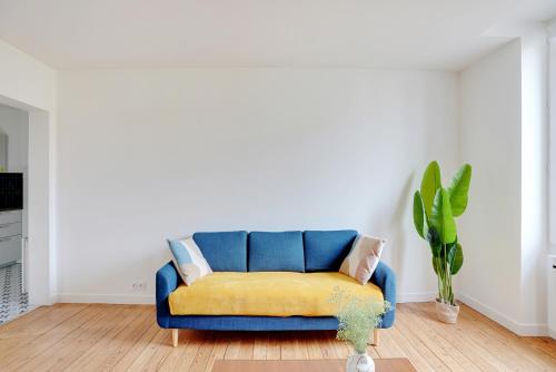 - un canapé bleu avec une couverture jaune dans le salon dans l'établissement Hypercentre Vincennes au pied du métro, à Vincennes