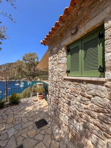 a stone house with a window with green shutters at Panta'kei in Stavros