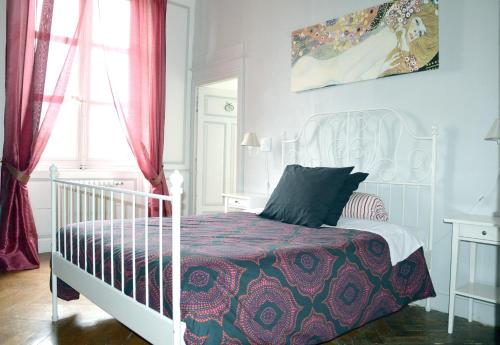 a bedroom with a white bed with a red curtain at Château De Matel in Roanne