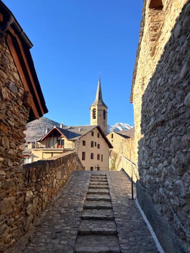 a stone path leading up to a church with a steeple at Apartaments Areny - L'Amfitriona in Esterri d'Àneu