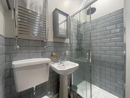 a bathroom with a sink and a toilet and a mirror at Greta House in Keswick