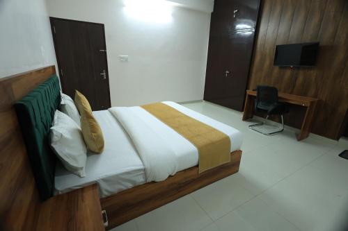 a bedroom with a bed and a desk and a television at Hotel Classic Crown in Jaipur